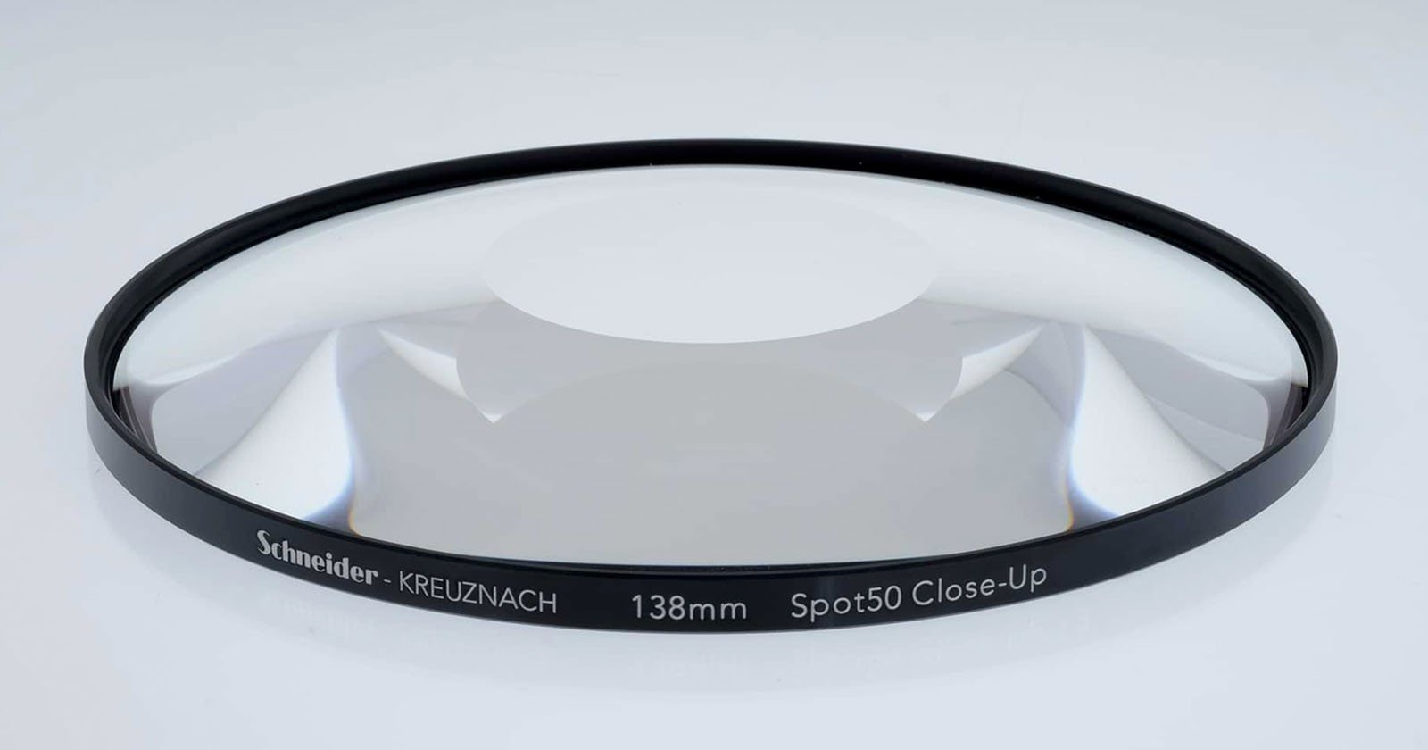 A close-up view of a Schneider-Kreuznach 138mm Spot 50 Close-Up lens filter. The filter is circular with a black rim displaying its specifications, and is placed on a neutral background.